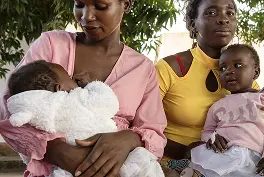 Imagem de duas mulheres amamentando embaixo de uma árvore.